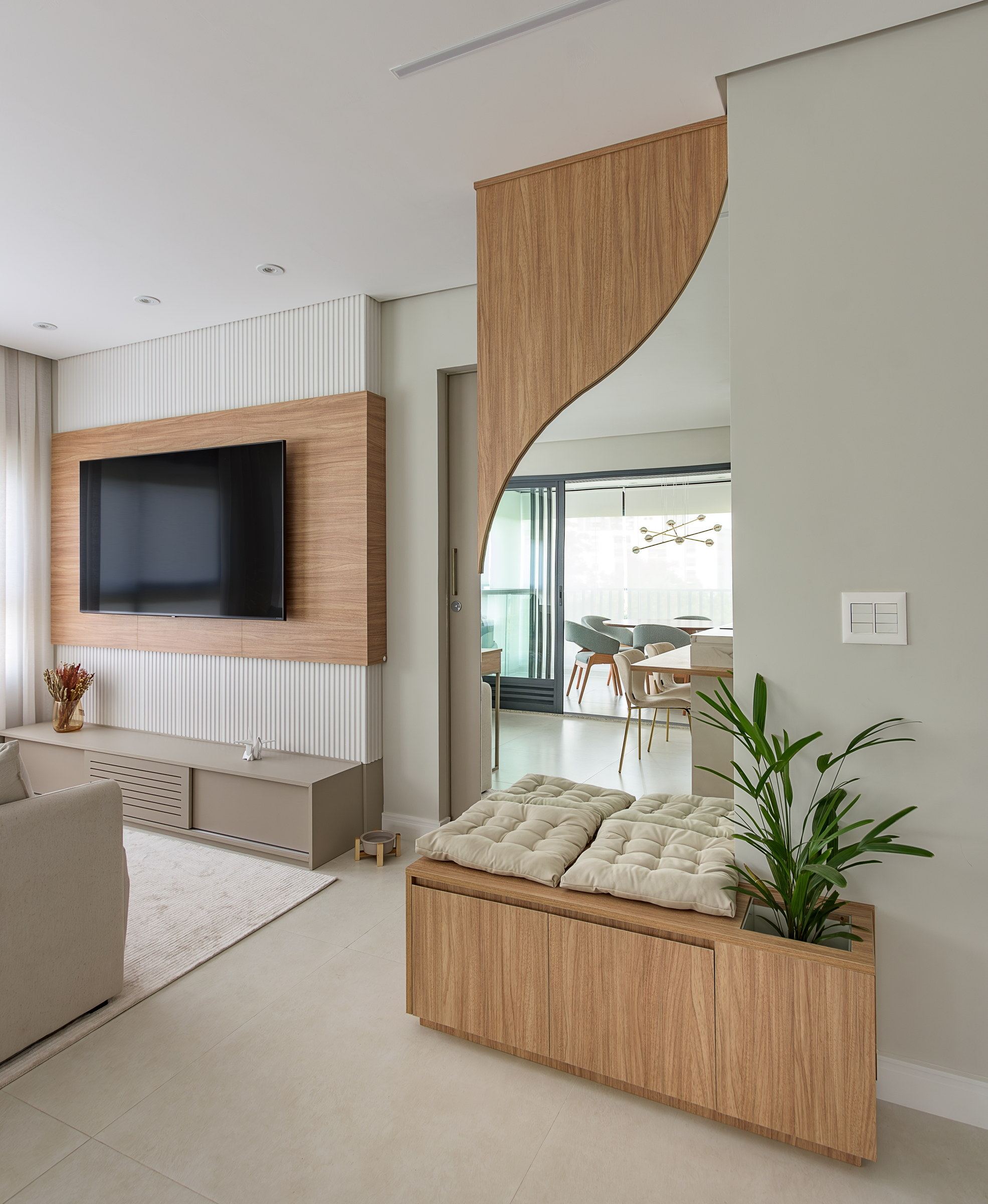 Parede da sala com acabamento curvo e ponto de TV embutido